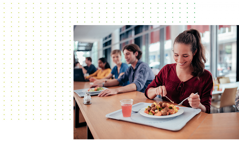 Eine Studentin sitz in der Mensa und isst